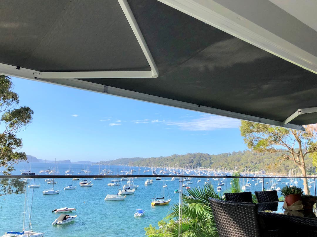 Awning installed on a balcony overlooking clear blue water with sailing boats parked
